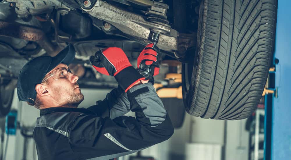 A mechanic performing a strut replacement on a lifted car.