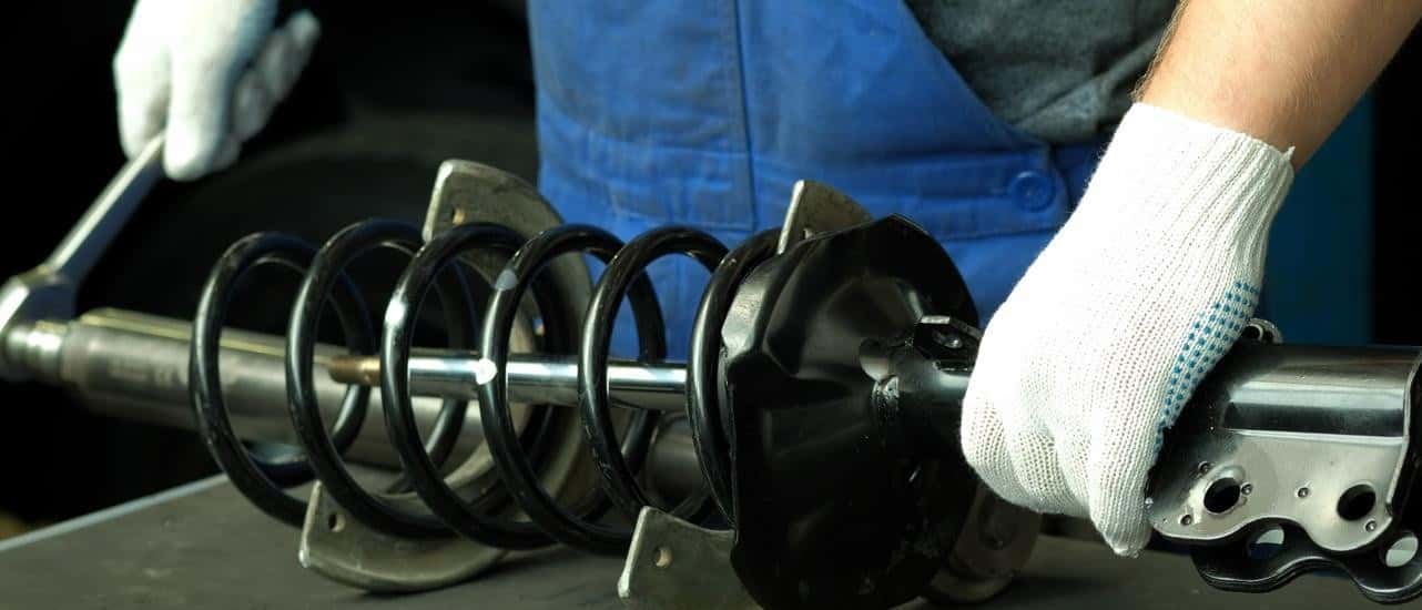 A mechanic is working on a strut at an auto shop.