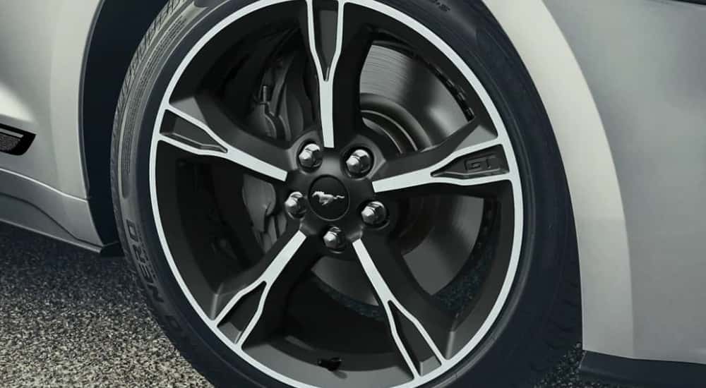 A close up show the front passenger tire on a silver 2023 Ford Mustang at a tire shop.