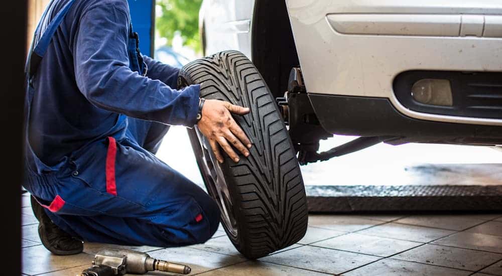 A mechanic installing a tire onto a white car.
