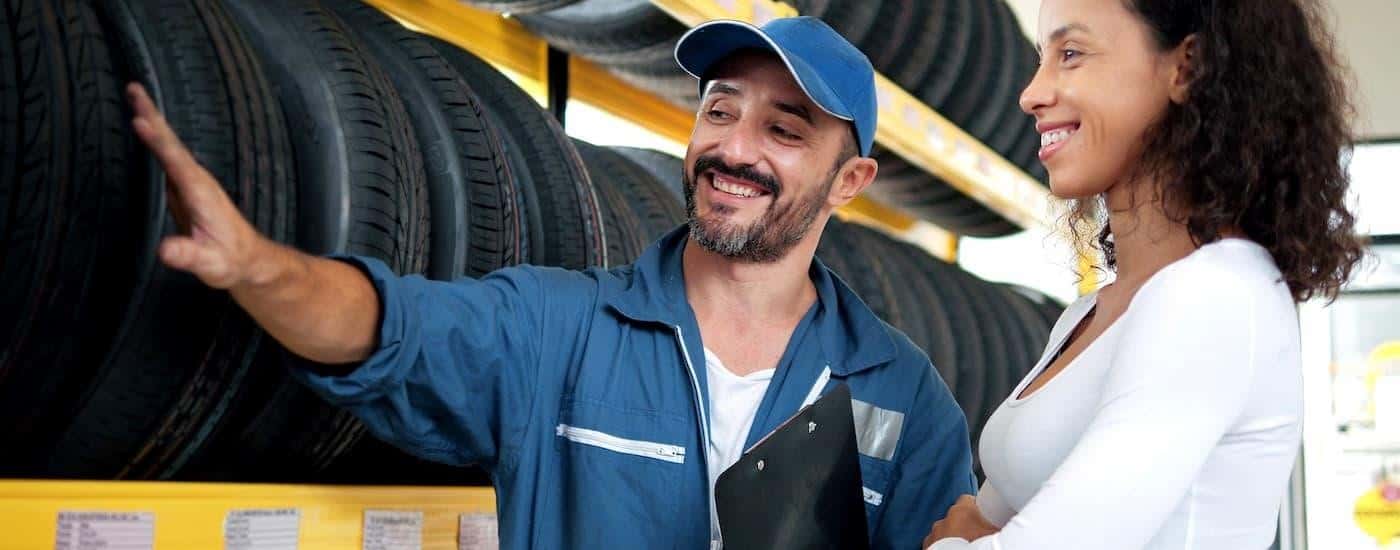 A mechanic and customer are at a tire shop going over tire options for her vehicle.
