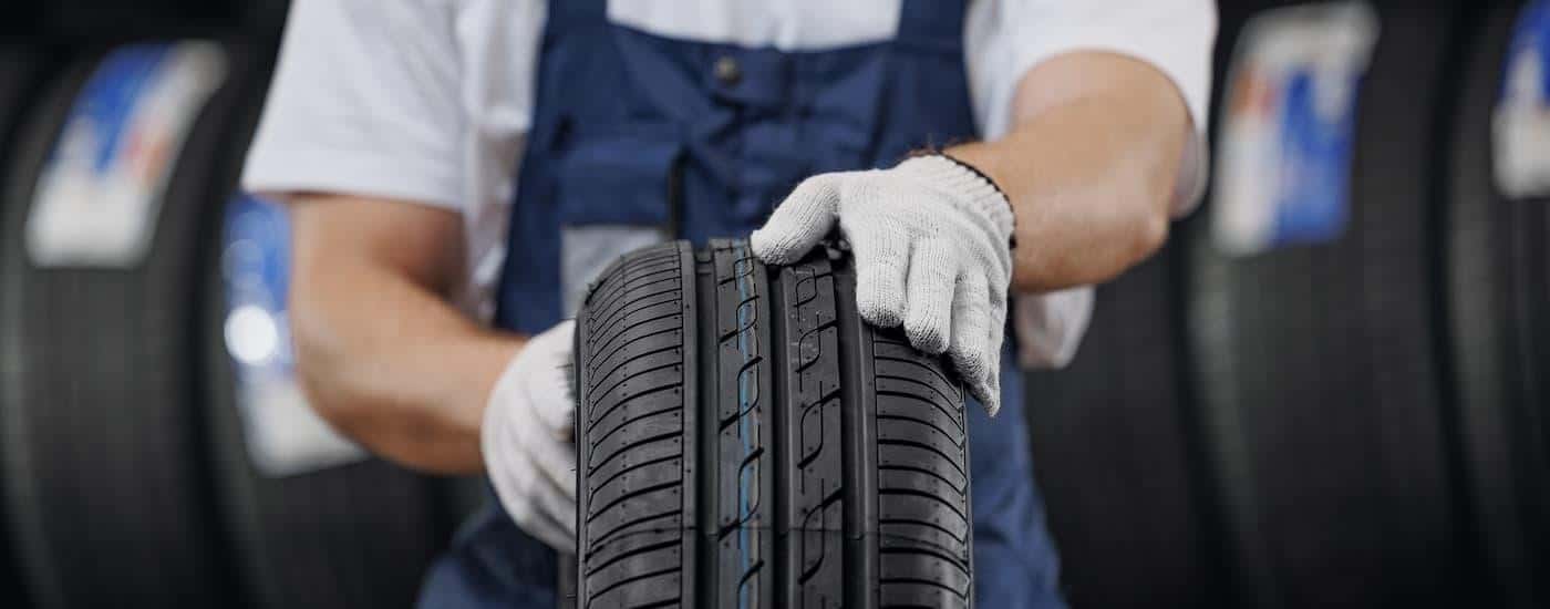 A mechanic is holding a new tire in a service bay.