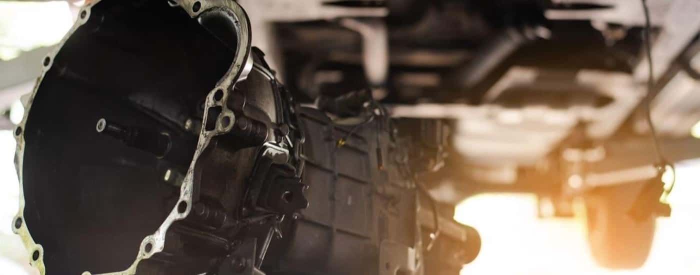 A transmission housing is shown near a vehicle on a lift.