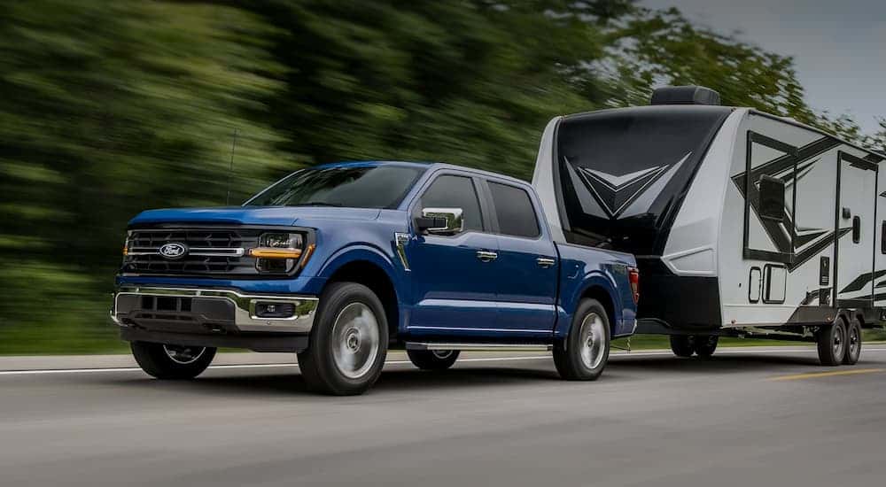 A blue 2025 Ford F-150 towing a camper.