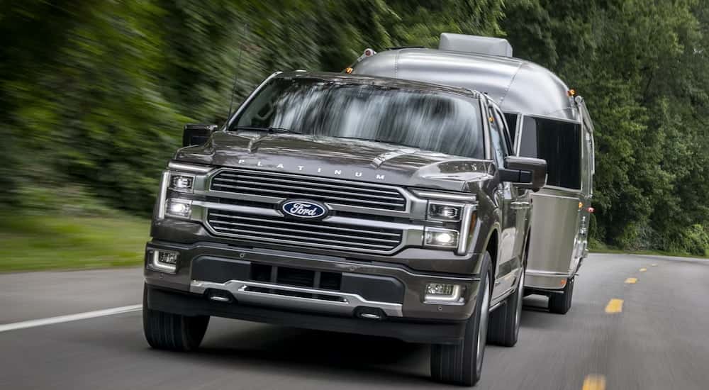 Front angle view of a black 2025 Ford F-150 Platinum Plus towing a camper van.