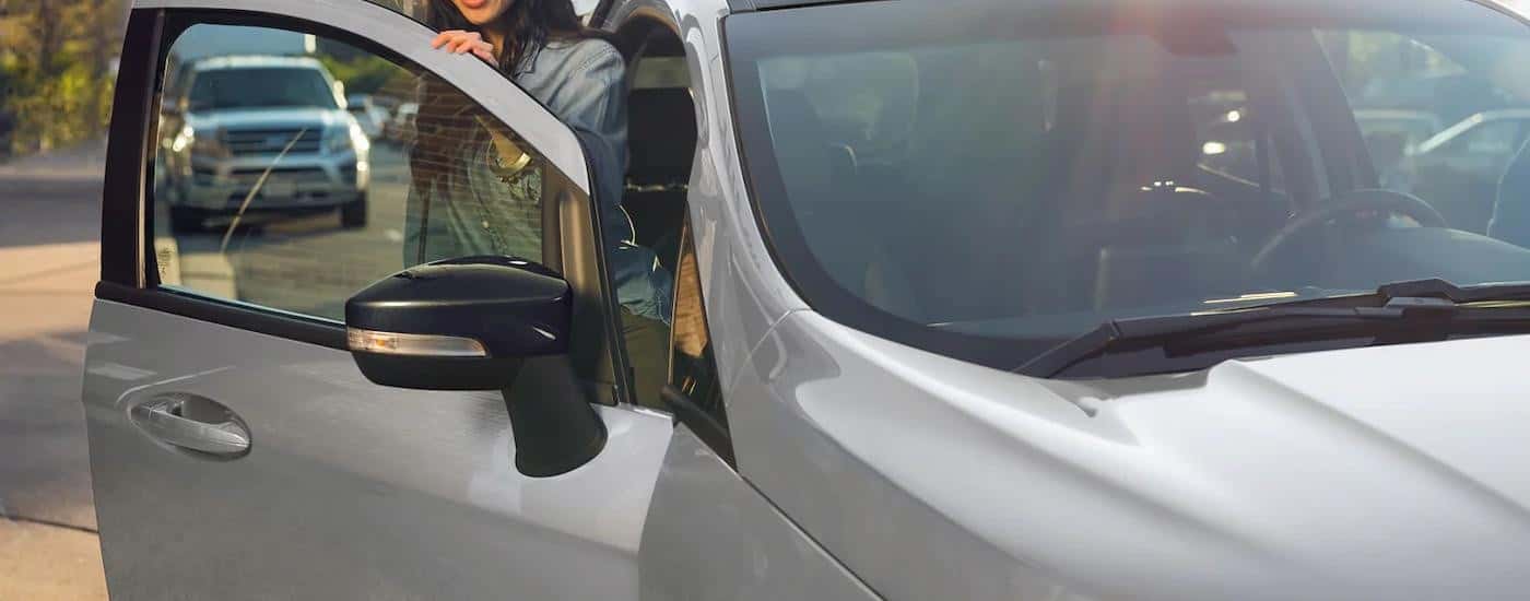 A woman is getting out of the passenger side of a silver 2022 Ford Ecosport.