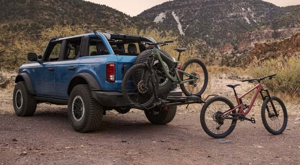 A set of bicycles near the rear of a blue 2023 Ford Bronco.