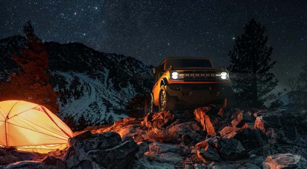 A popular used Ford Bronco for sale, a orange 2022 Ford Bronco, is shown from the front parked in the mountains at night.