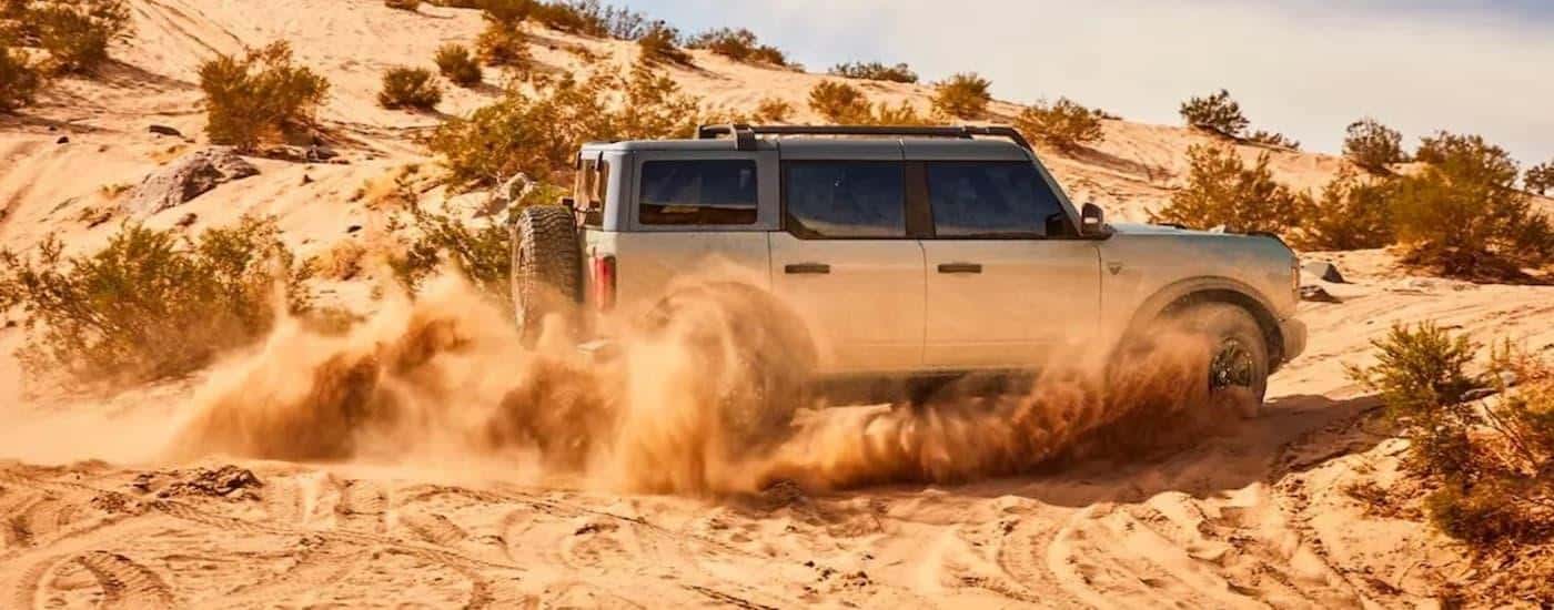 The tan interior of a 2021 Ford Bronco is shown off-roading after looking at a used Ford Bronco for sale.