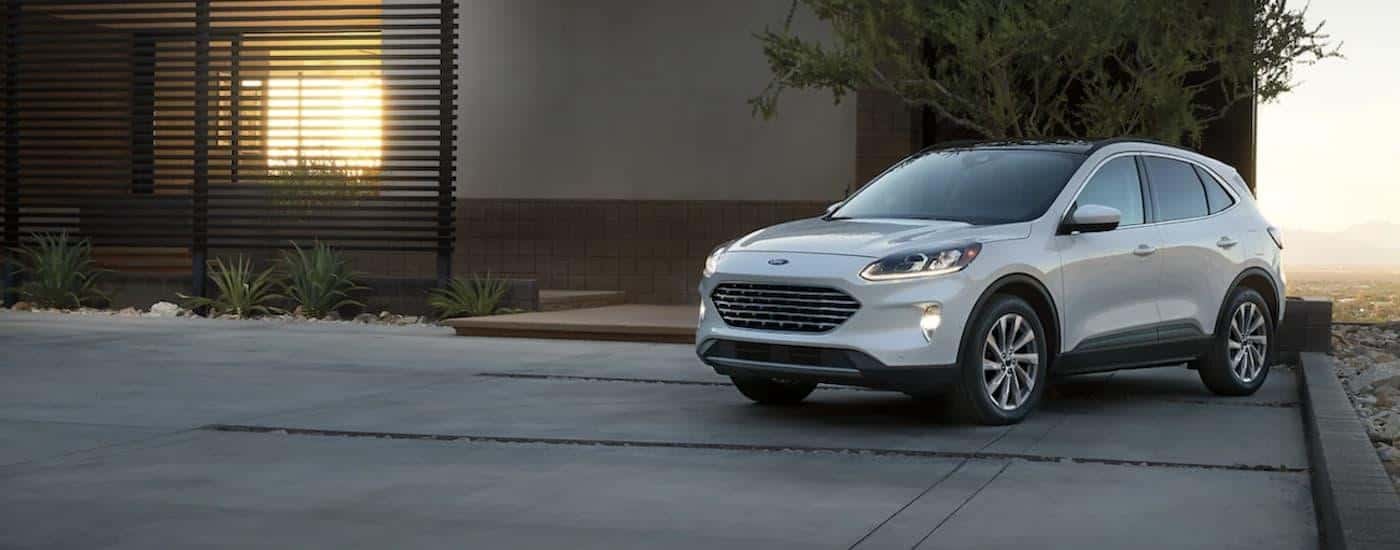 A silver 2021 Ford Escape Hybrid is shown parked in front of a modern house.