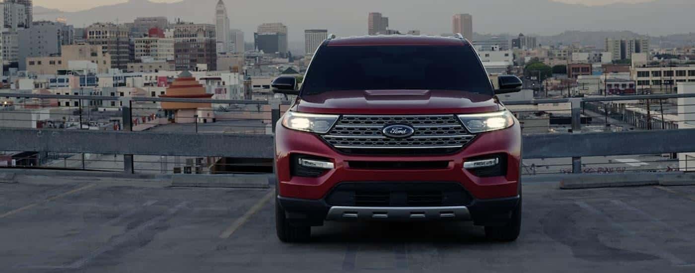 A red 2021 Ford Explorer is shown parked in front of a city.