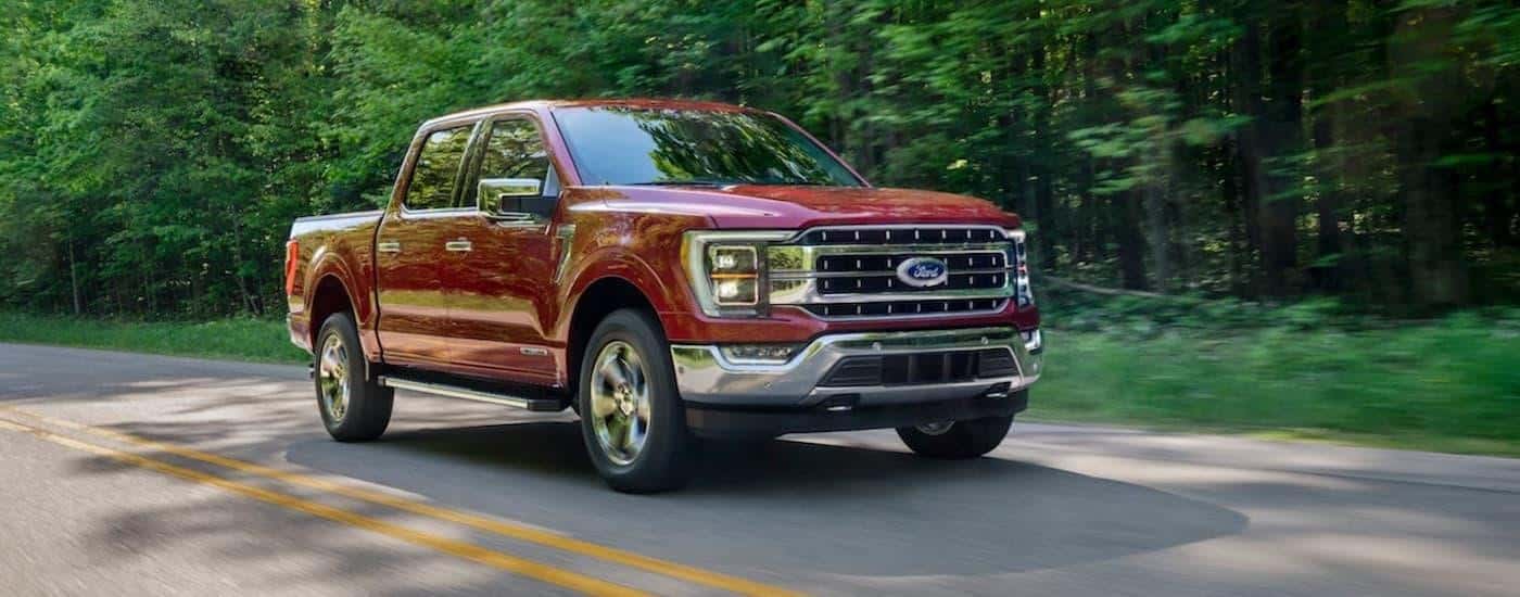 A red 2021 Ford F-150 is shown driving on an open road after leaving a used Ford dealer in Loganville.