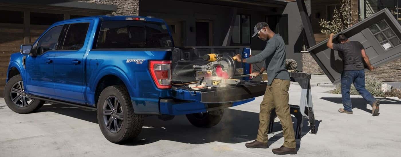A blue 2021 Ford F-150 Sport is shown from the side on a construction site.