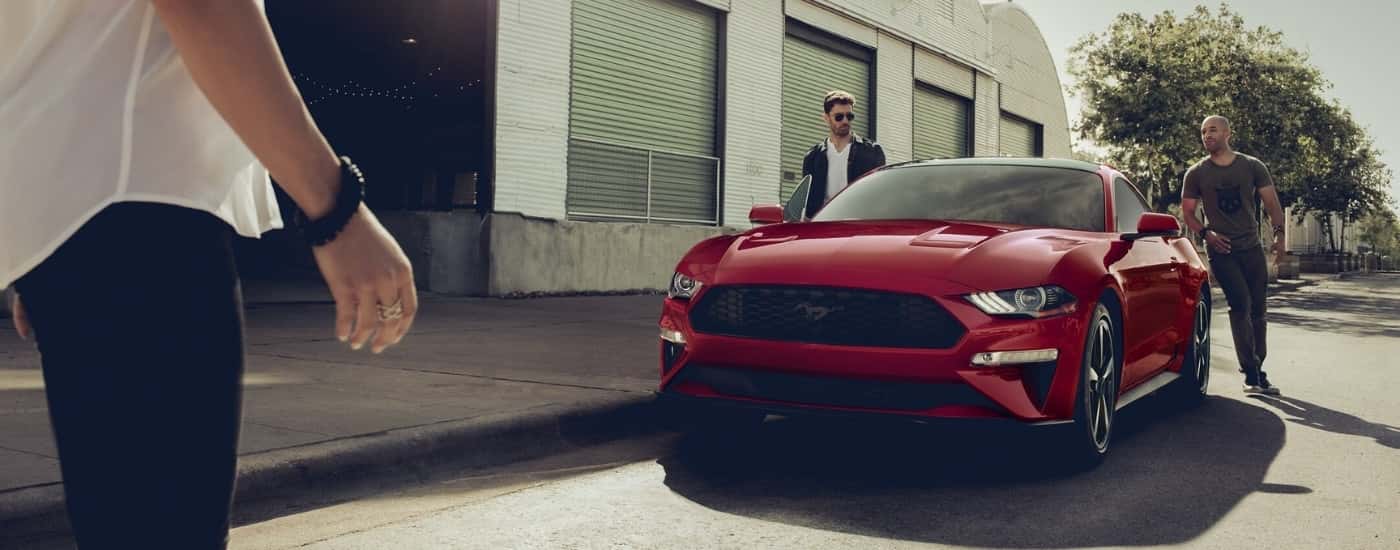 People are shown approaching a red 2021 Ford Mustang GT.