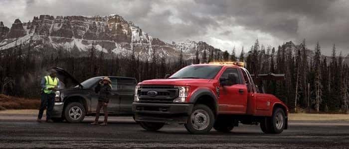 Ford commercial towing truck on side of road assisting car