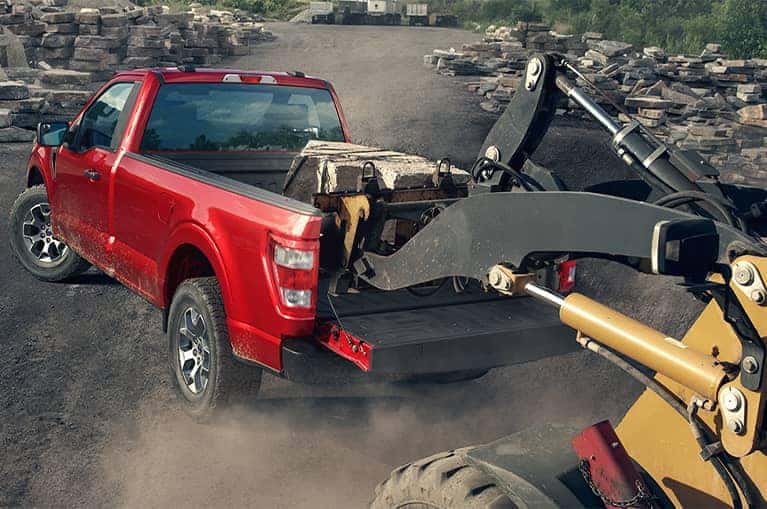 Red 2021 Ford F-150 hauling construction equipment