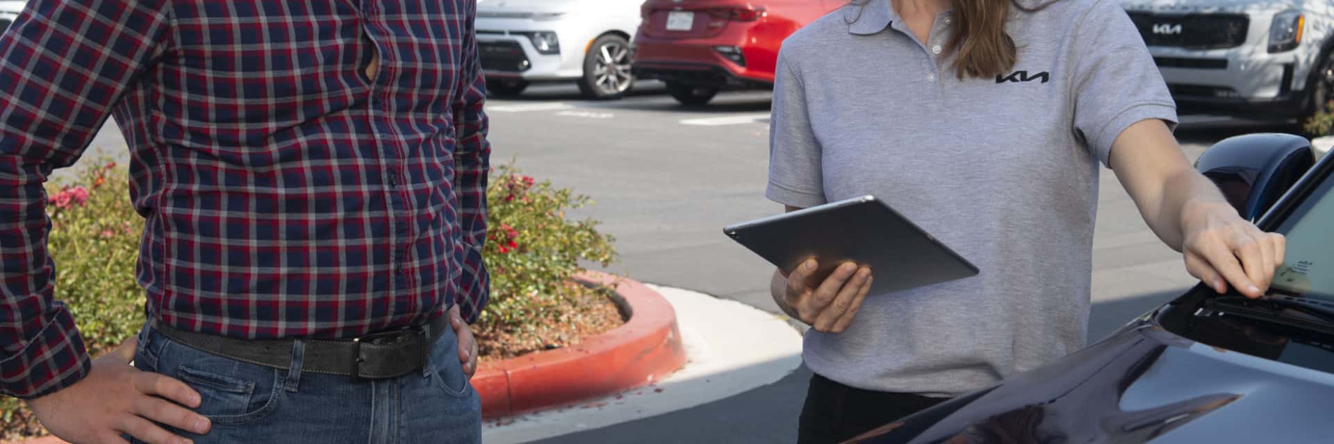 Kia employee helping a customer with a vehicle purchase.