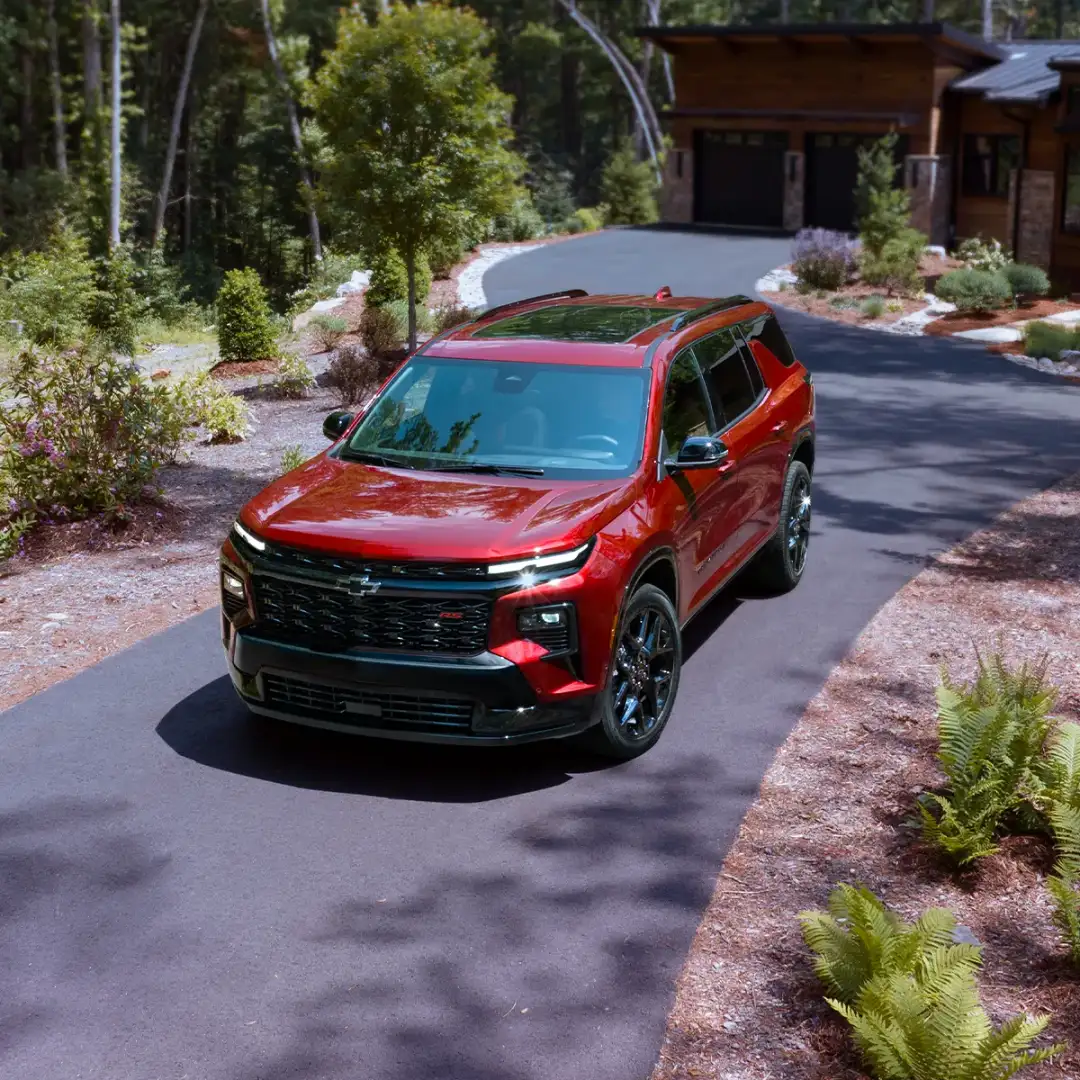 Red 2024 Chevrolet Traverse parked in a driveway in front of a house