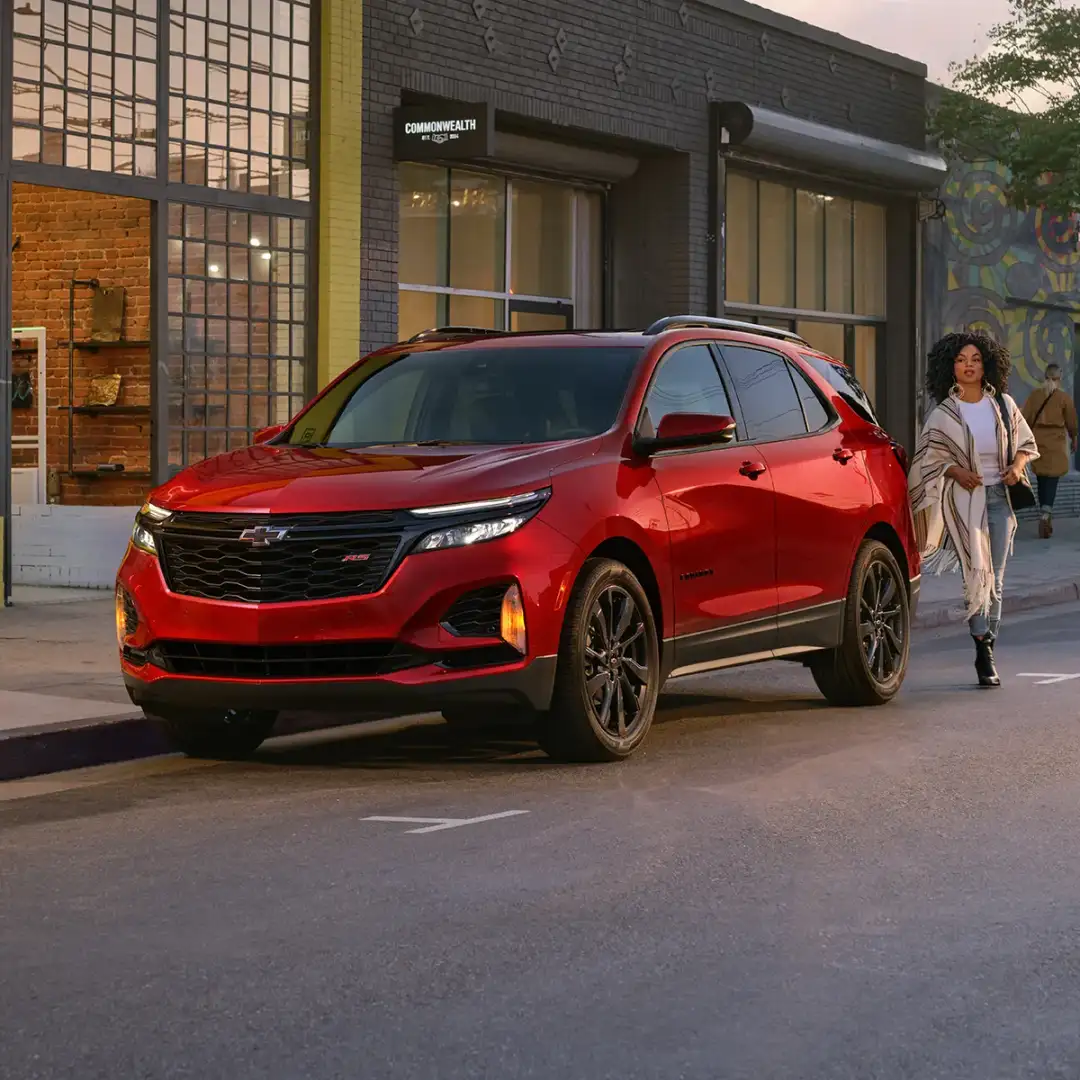 Stylish person walking beside a 2024 Chevrolet Equinox parked outside a building