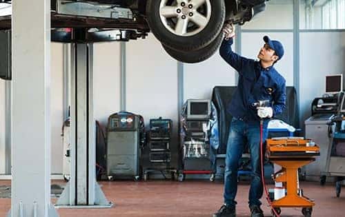 service technician examining a tire on a raised car