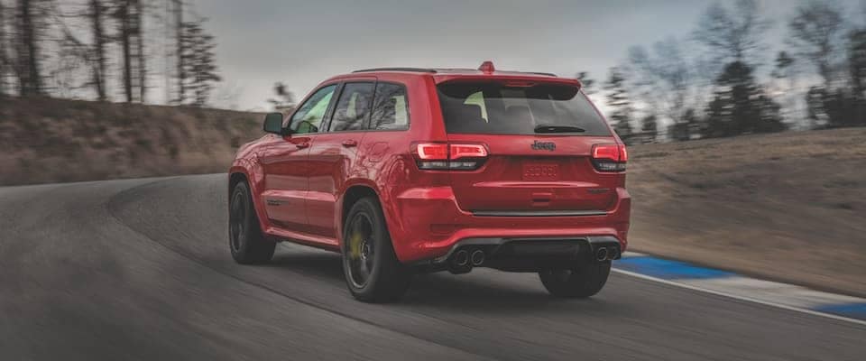 A red Jeep Grand Cherokee driving down an open track