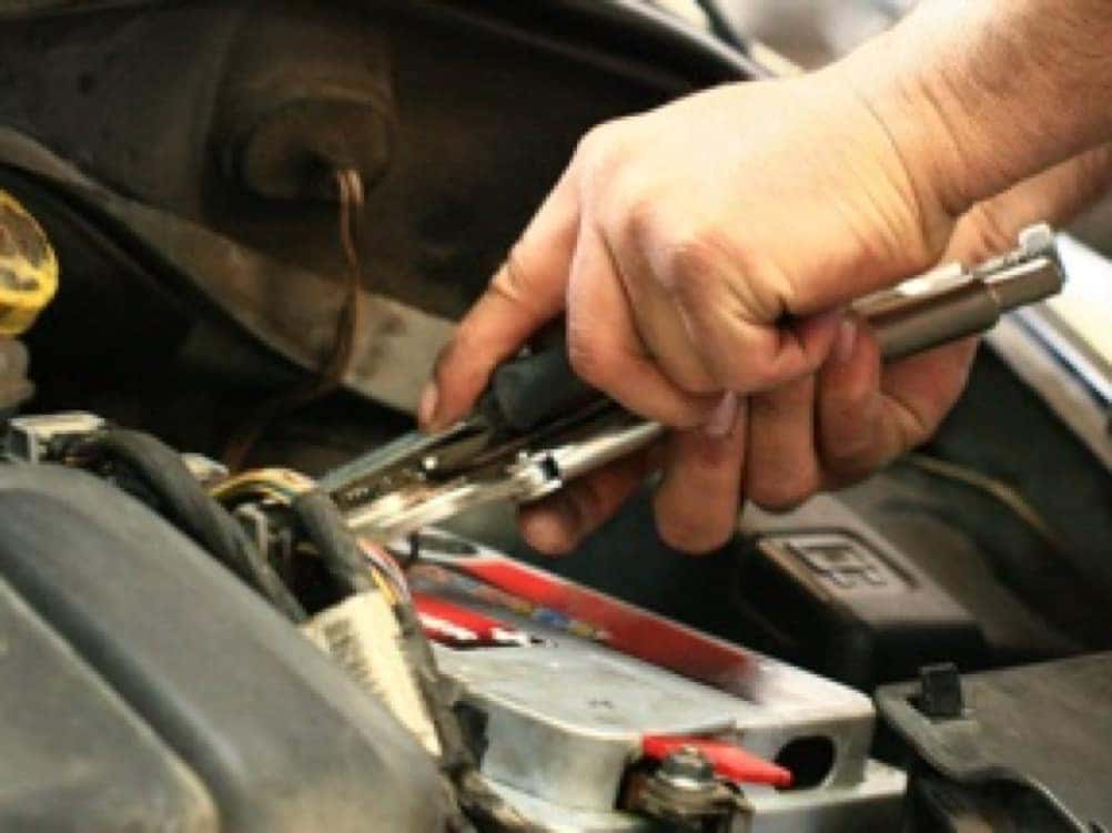 Battery picture of technician hands unscrewing battery post