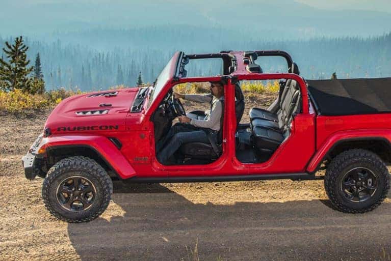 2024 Jeep Gladiator driving on dirt road overlooking a forest valley