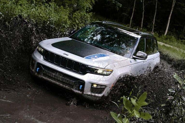 2024 Jeep Grand Cherokee spalshing through a deep mud puddle