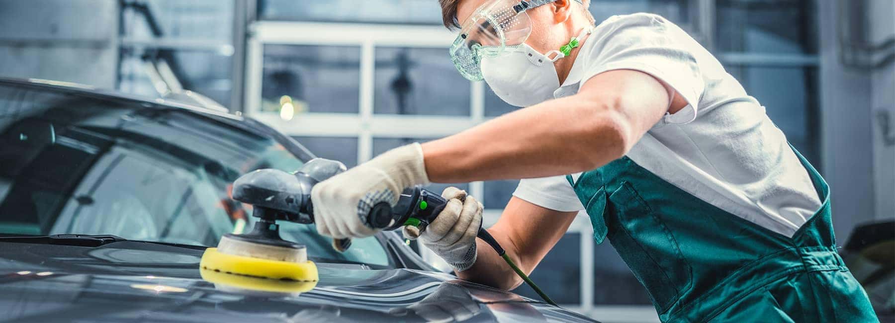 Mechanic buffing the paint of a car at an auto body shop