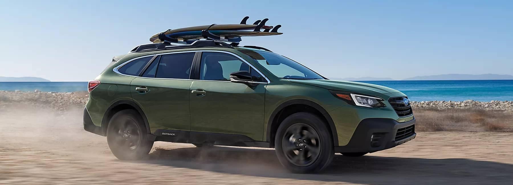 2022 Subaru Outback-side view-driving down beach-ocean in background-green