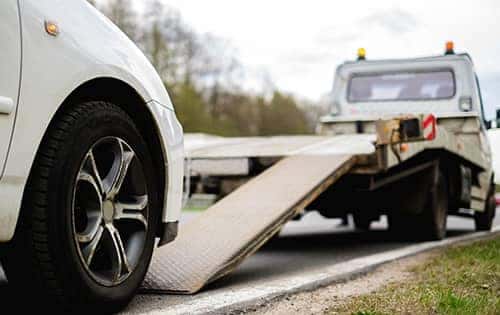 car driving onto tow truck lift