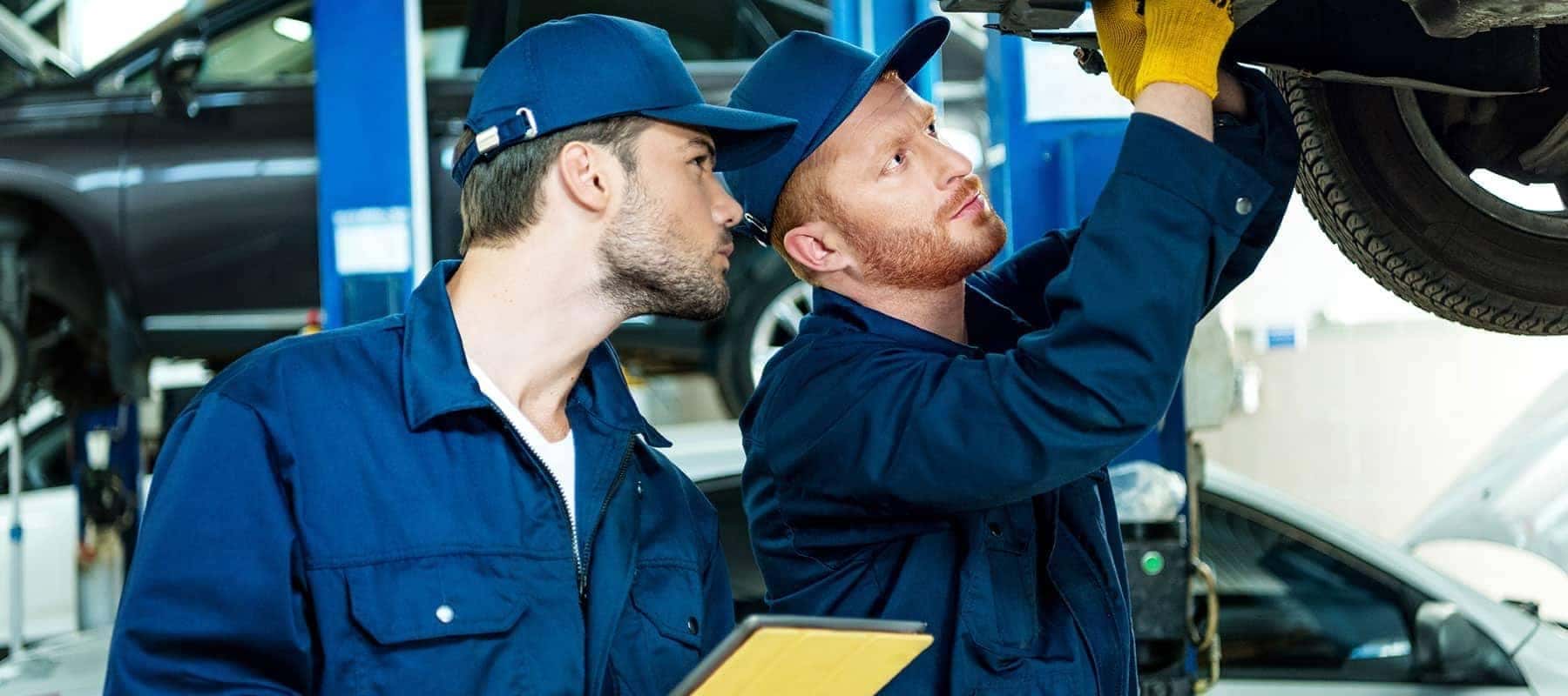 Two-Mechanics make repairs to undercarriage of vehicle