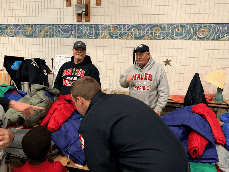 Volunteers standing by coats on table