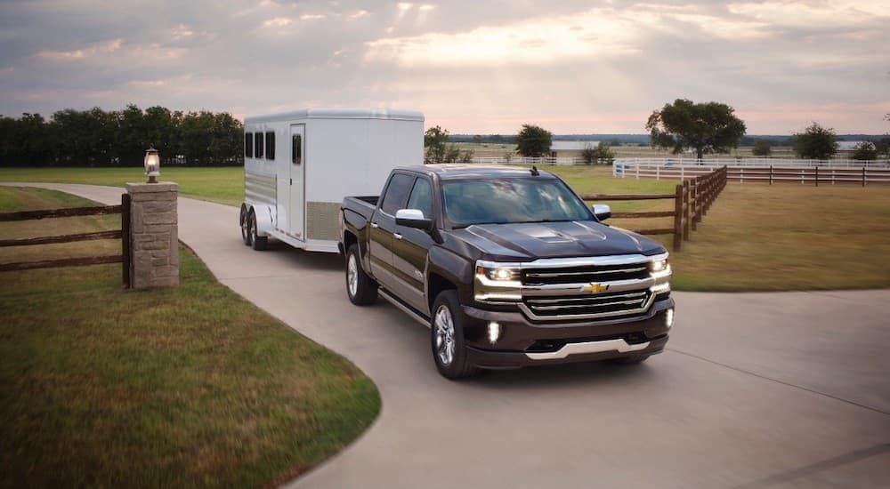 A black 2017 Chevy Silverado, which is popular among used trucks for sale, is towing a horse trailer at a farm near Cincinnati, OH.