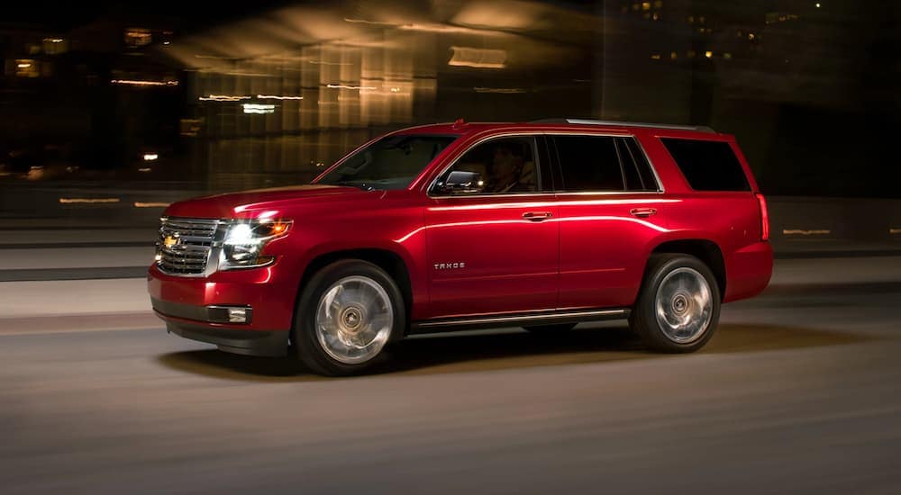 A red 2020 Chevy Tahoe is driving on a city street at night in Cincinnati, OH.