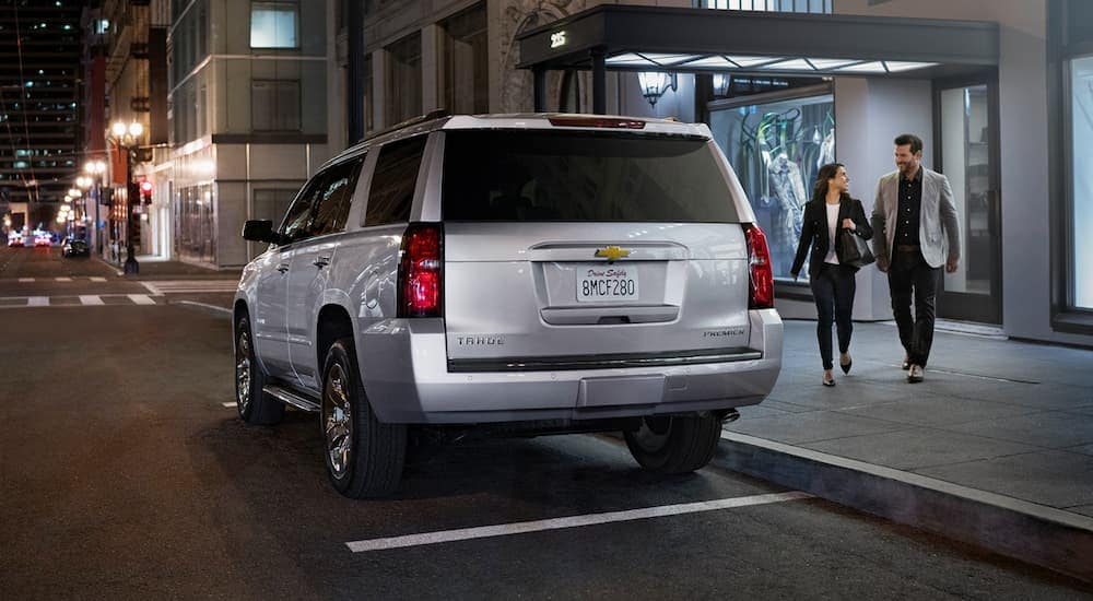 A silver 2020 Chevy Tahoe is parked on a city street at night.