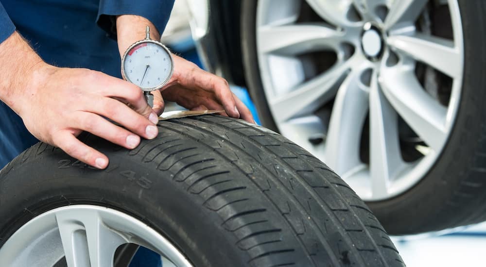 A mechanic is measuring tread depth on a tire at a tire dealer in Cincinnati, OH.