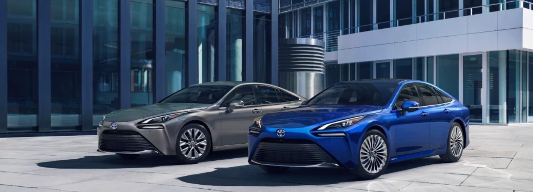2022mirai-hero-2cars-front-angleview-glass-buildings-blue_grey