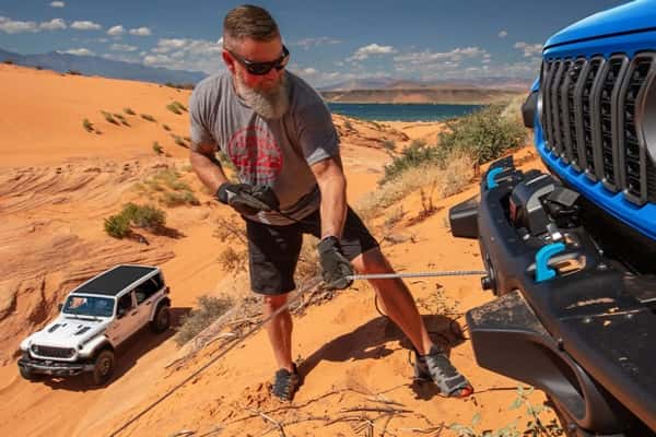 2025-Jeep-Wrangler-4xe-with-man-pulling-a-tow-cable-off-thr-front