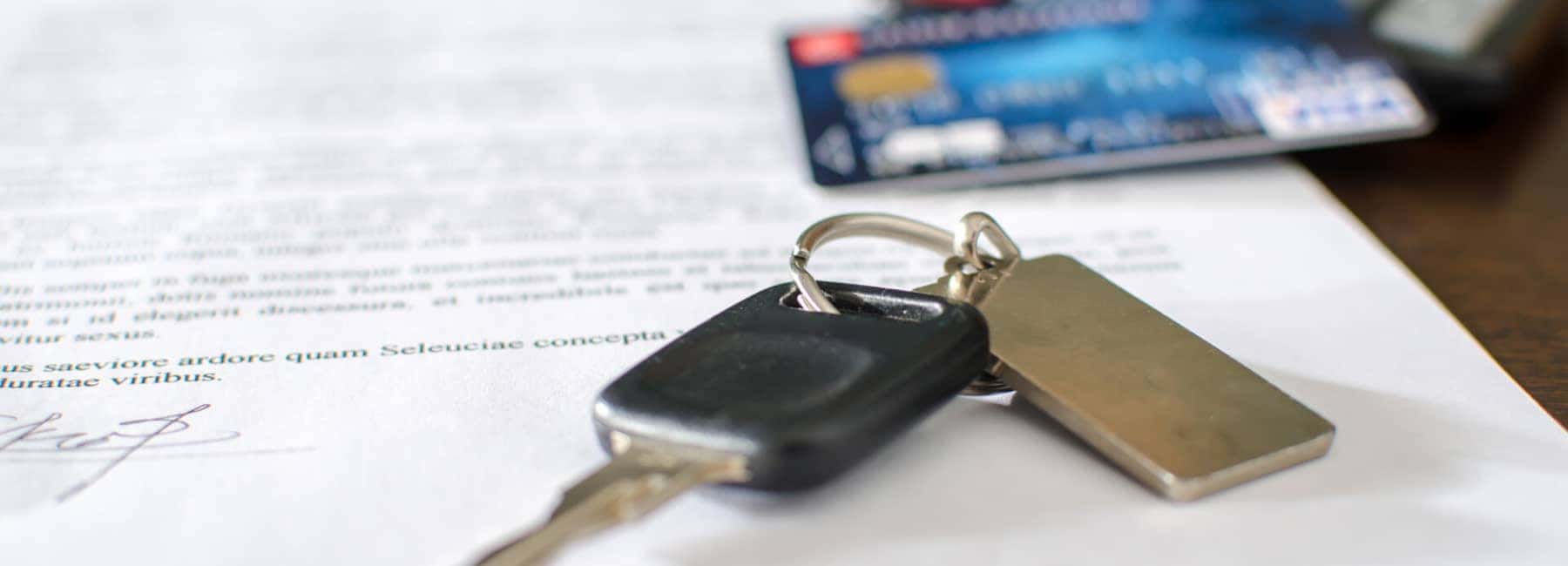 Car key and credit card on a signed sales contract
