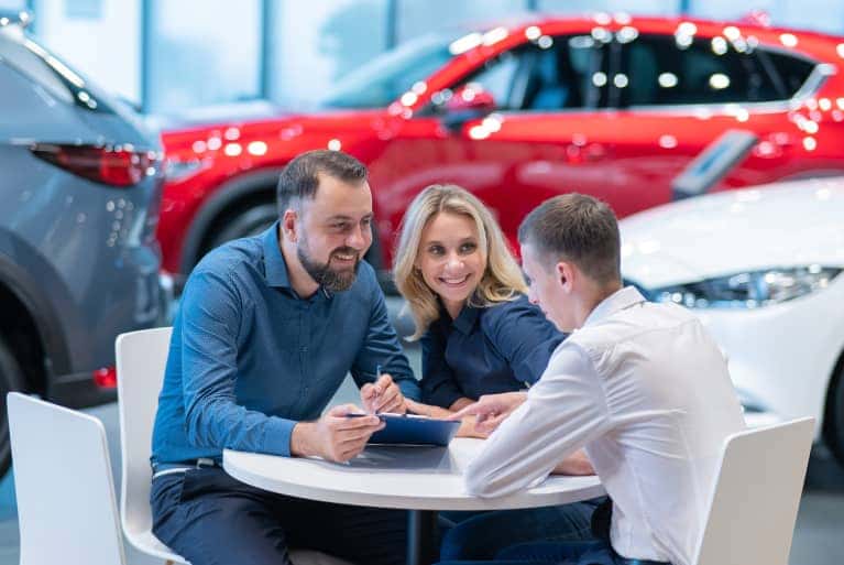 Two people in a dealership showroom sitting with a finance advisor