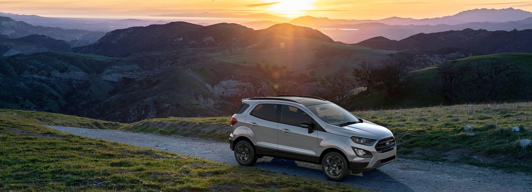 Silver 2021 Ford EcoSport overlooking the sunset behind a mountain range