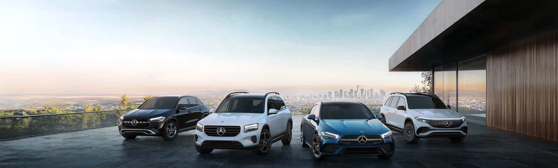 A lineup of Mercedes-Benz vehicles with the city in the background