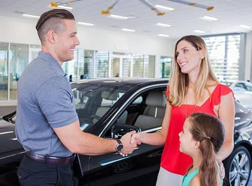 Salesperson shaking the hand of a customer after a purchase of a vehicle