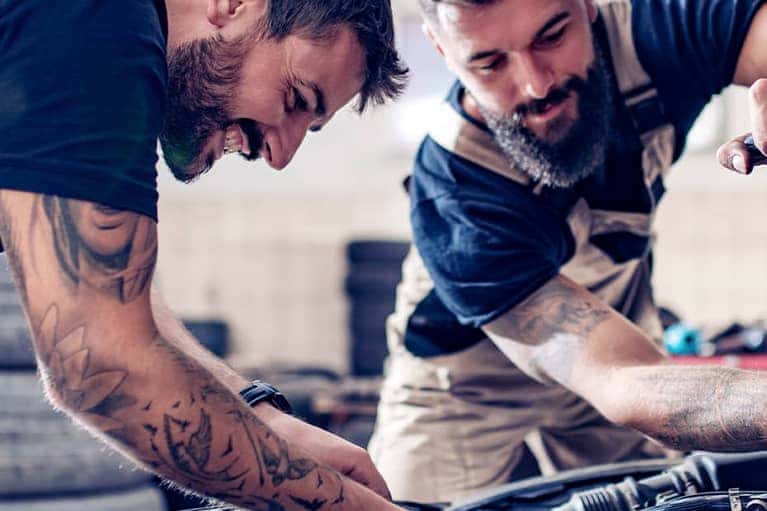 Two mechanics working on a vehicle