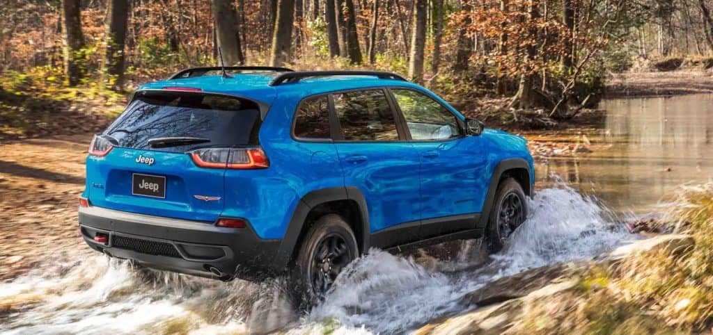 Blue Jeep Cherokee SUV Water Fording Trees