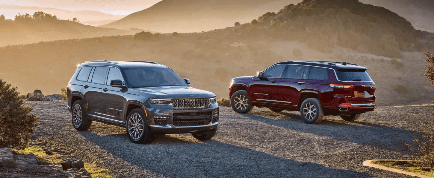 Two Jeep Grand Cherokee L parked by mountains