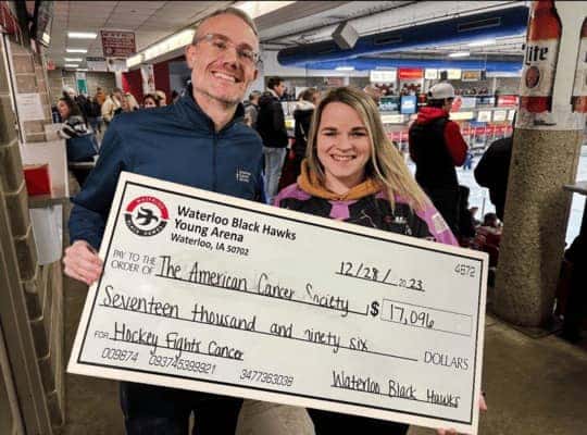 Two people smiling holding a check