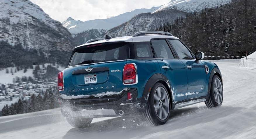rear of blue MINI driving on road with snow
