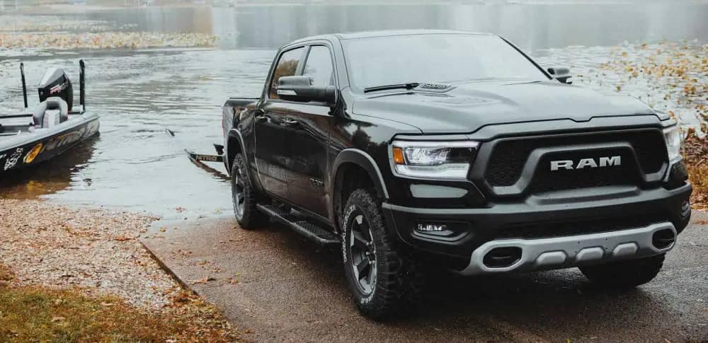 The 2022 Ram 1500 with a boat trailer parked at the edge of a lake.